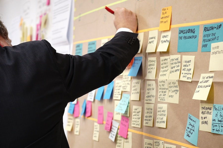 Mann schreibt etwas auf eine Wand mit Post-its